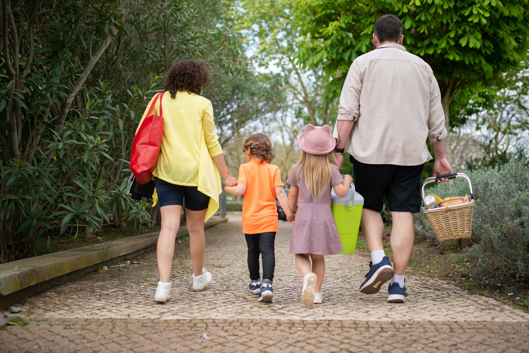 A family enjoying a walk in a picturesque Portuguese park carrying a picnic basket.